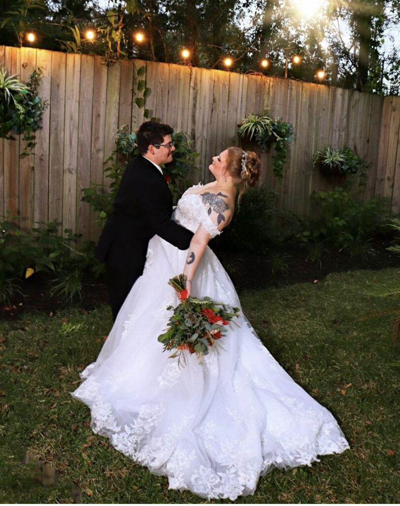 Bride and groom share a joyful dance outdoors at sunset.