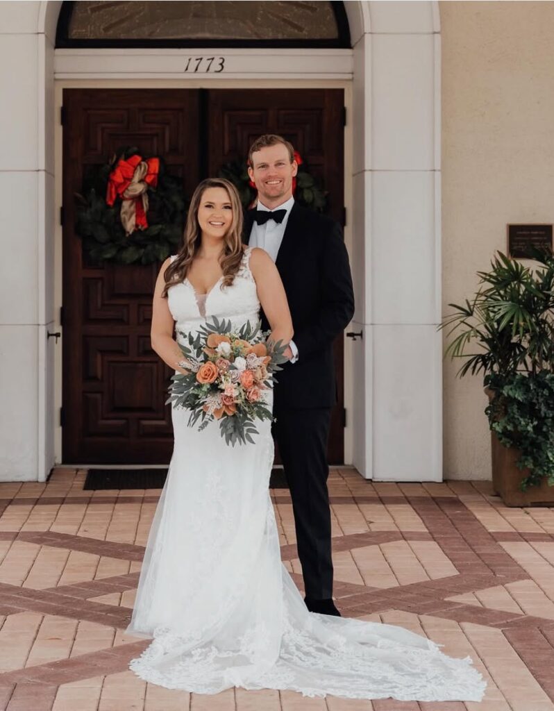 Bride and groom posing in front of a building on their wedding day.